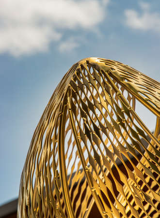 Bangkok, Thailand - 30 Jun 2021 : Golden steel sculpture for decorative attractive at park. Architectural structure consists of decorative metallic, Photographed from a low angle against a blue sky in the background. Selective focus.のeditorial素材