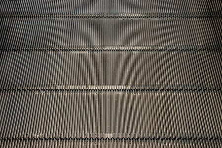 Detail shot of moving steps at the bottom of a conventional escalator with sensor. No focus,...