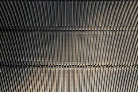 Detail shot of moving steps at the bottom of a conventional escalator with sensor. No focus,...