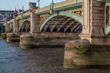 London, England - Apr 20, 2019 : Side view of Beams and Rivets-structure under the Bridge span in the setting sun. Large metal bridge over water, No focus, specifically.のeditorial素材