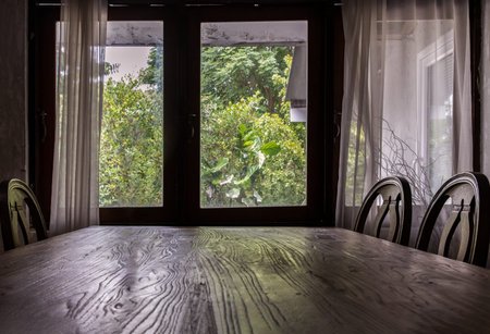 Wooden eating table and chairs in dining room. Wooden window and white curtains in traditional house, No focus, specifically.の写真素材