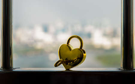 Golden heart shaped love padlock and key over on Stainless steel balcony railing. Valentine's day concept, Copy space, No focus, specifically.の写真素材
