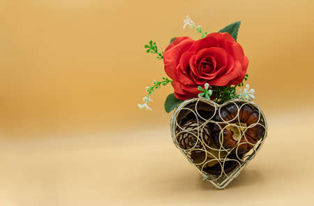 Red rose flower placed over on Dry fruit box silver heart shape on orange background. Valentine's day background concept, Copy space, Selective focus.の写真素材