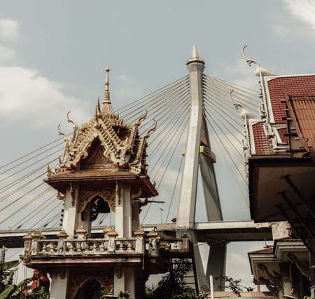 Bangkok, Thailand. Mar - 12, 2022 : Beautiful view of Buddhist thai temple with suspension bridge background can coexist perfectly. Selective Focus.の写真素材