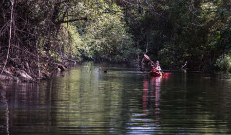 Nakhon Ratchasima, Thailand. Mar - 20, 2022 : Two young woman adventurous people having fun together while red kayaking on brook in forest. Having fun in leisure activity, Nature and Tourist attraction concept. No focus, specifically.のeditorial素材