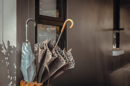 The sunlight shines on the Brown and blue umbrellas in umbrella storage make from wood beside the...