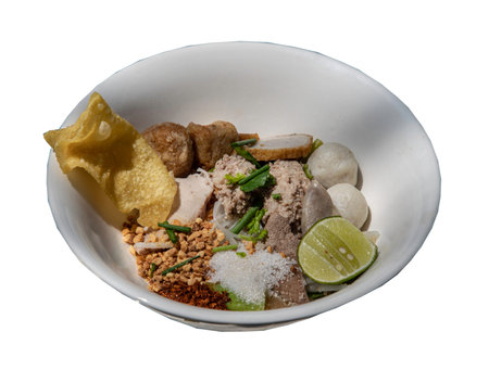 Traditional steamed thin rice noodles (Small noodles) with fish balls, shrimp meatballs, steamed ground pork, fried wonton, suger, ground peanut, ground dried chili and slice lime without soup in white bowl isolated on white background . Asian style food, Selective focus.の写真素材
