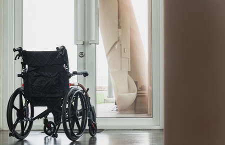 The back of an empty wheelchair with no one sitting as if looking outside through a glass door. Near the exit glass door with a blurred outside view of the garden in background. There is always hope in life, Copy space, Selective focus.の写真素材