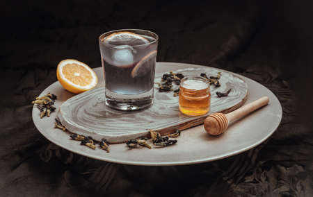 Blue and violet color butterfly peaflower juice (Clitoria) mixed with lemonade and ice decorated with yellow lemon fruit sliced served with honey and dry butterfly pea flowers on dark background. Healthy detox herbal drink, Space for text, Selective focus.の素材 [FY310187773767]