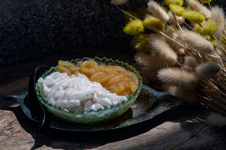 Kanom pla krim khai tao or Sweet rice noodles with coconut cream in glass bowl served with black spoon. Traditional thai dessert, Copy space, Selective focus.の写真素材
