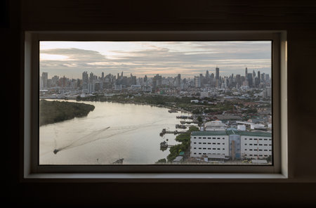 Bangkok, Thailand - Jul 04, 2022 : Skyscrapers along Chao phraya river in the evening time. Seen through a bedroom window frame. The beautiful view of Bangkok city, Selective focus.のeditorial素材