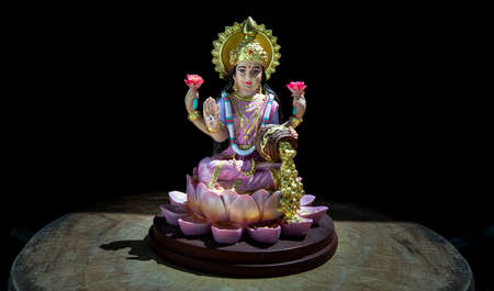 Hindu cosmos Maha laxshmi statue decorated with Flower Garland on black background. Statue of Goddess of Wealth, Copy space, Selective focus.の写真素材