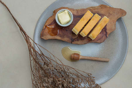 Slices of four butter cakes in wooden box served with butter and honey from above. Selective focus.の写真素材