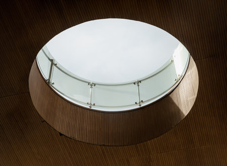 Looking up to the white sky through modern channel round circular ceiling. The sun's rays break...