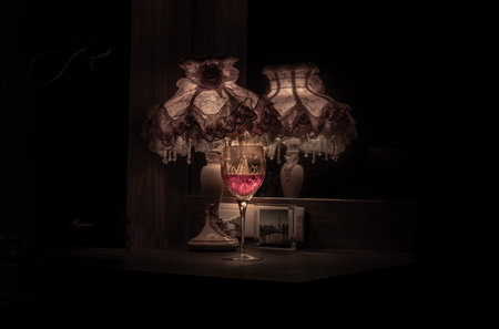 Bangkok,Thai - Oct 01, 2022 : A glass of red wine in the dim light of Vintage lamp with reflection from mirror. Light and Shadow, Dark tone, Copy space, Selective focus.の写真素材