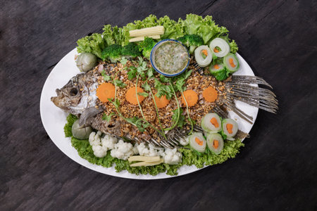 Delicious deep fried fish giant gourami topping with crispy garlic and Herb salad with Spicy on...