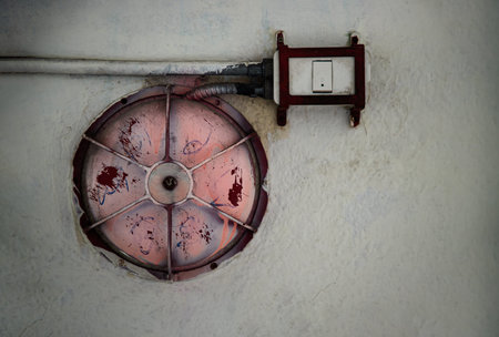 Old and dirty Red fire alarm bell and Electrical wires on white concrete wall at old underpass. Old...