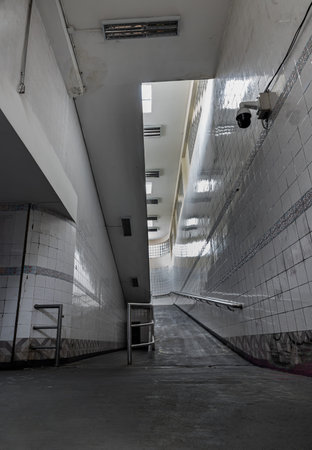 Bangkok, Thailand - Sep 30, 2022 : Stairs leading to interior view of public underpass with white tiled walls and CCTV. Space for text, Selective focus.のeditorial素材