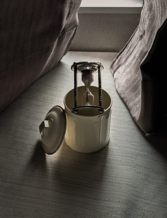 Sandglass or Hourglass on the trash can with open lid on the window cushions seat in the room with...