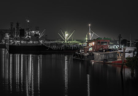 Bangkok, Thailand - 07 Nov 2022 : Small harbor with cargo ships and a small boat were parked on the Chao Phraya River at night. Focus and blur.の写真素材