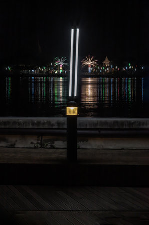 Riverside thai local temple fair work decorated with different colored lights and sky in night time. View from the opposite bank of the river, Celebration, Space for text, Dark tone, No focus, specifically.の写真素材