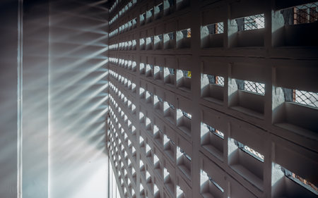 The sunlight shines through light channels wall of old gymnasium. Concrete walls have holes for sunlight to penetrate through the holes from the outside, Light and shadow concept, Space for text, Selective Focus.の写真素材