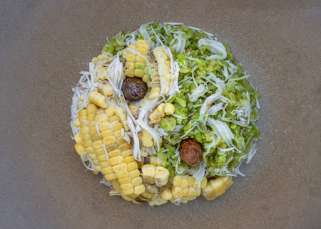 Top view of Pounded unripe rice Flakes Cereal (Glutinous rice is processed into "Khao Mao Khlook") and Steamed sweet corn Mixed with grated young coconut flesh looks like of a yin yang symbol on A ceramic plate. Traditional thai food dessert or snacks, space for text.の写真素材