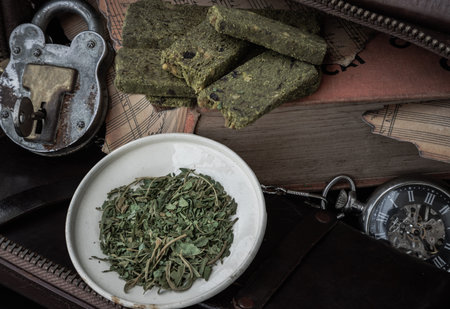 Homemade Cannabis Snack Sticks on the Old Music Notebook with the Chopped Cannabis leaves in the...