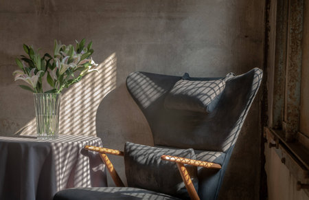 A Wooden Upholstered Chair and the Bouquet of Flowers in a Glass Vase on Table in the Room with Bare...