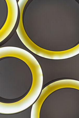 Look up to the round ceiling mounted light fixtures. Yellow circular ring shaped lamps hang under ceiling, Architecture and interior lighting design, Abstract lighting background, Space for text, Selective focus.の写真素材