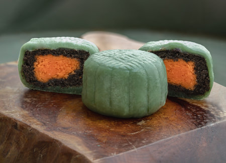Delicious green mooncakes is filled with taro, black sesame and golden thread egg on wooden cutting board. Which gives you luck and wealth. Space for text, Selective focus.の写真素材