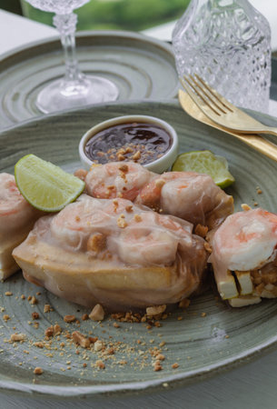 Homemade riceberry rice paper spring rolls stuffed with shrimp (prawn), sliced chicken, tofu and egg served with sliced lime and chili sauce sprinkle with ground peanuts on ceramic plate. Selective focus.の写真素材