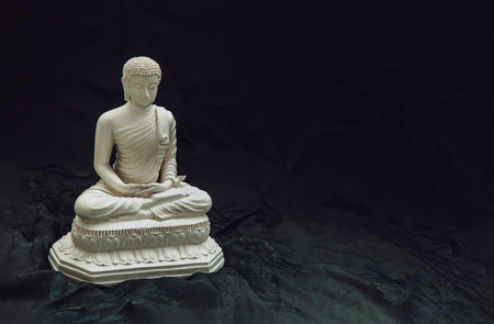 White figurine of siddhartha gautama buddha sculpture statue with dark background. Space for text, Selective focus.の写真素材