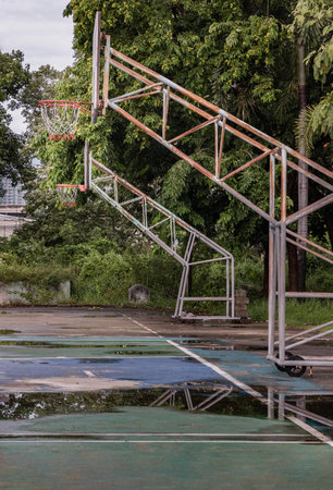 Two basketball wooden backboards with the hoop metal rings and the white and red net on the cement court are at old cemetery park on a rainy day. Space for text, Selective focus.の写真素材