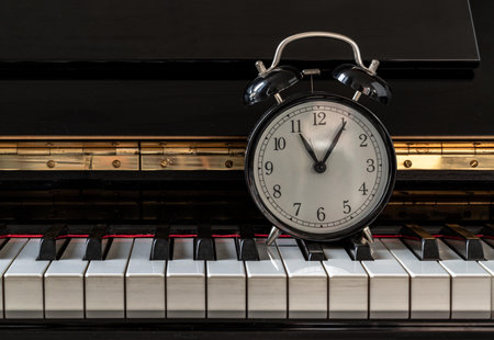Black alarm clock stand on the Piano Keyboard. Time for music concept. Space for text, Selective focus.の写真素材