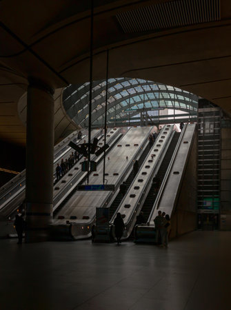 London, England - Oct 16, 2023 - People riding the escalators inside of the Canary Wharf underground tube station. It is a station on the Jubilee Line, between Canada Water and North Greenwich, Copy space, Selective focus.のeditorial素材