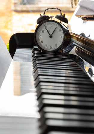 Black alarm clock stand on the Piano Keyboard. Time for music concept. Space for text, Selective focus.の写真素材