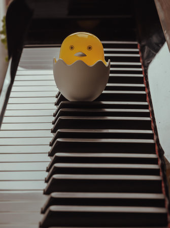 Baby chickÂ cartoon sitting in broken egg stand on the Piano Keyboard. Yellow cute chicken hatching from egg, Space for text, Selective focus.の写真素材