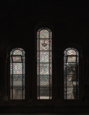 London, UK - Nov 01, 2023 - Coriander stained glass on the elevation windows are contained within large stone arches in the main hall of The natural history museum. Pattern of The Stained glass windows, Victorian stained glass, Space for text, Selective focus.の写真素材