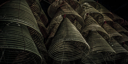 Multiple large yellow incense coils hanging in stacks from the Ceiling in a Chinese shrine. Large Bell Shaped Spiral Incense Coils, Focus and blur.の写真素材