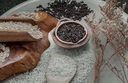 Various types of rice : Brown rice, Jasmine rice, Riceberry and dried flowers on ceramic background. Organic raw rice collection, Healthy food and diet concept, Overhead view, Selective focus.の写真素材