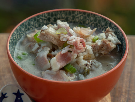 Hot Boiled rice or Rice porridge with Pork spare ribs soup, Ham and fresh cut celery in orange ceramic bowl. Healthy breakfast food, Top view, Space for text, Selective Focus.の写真素材