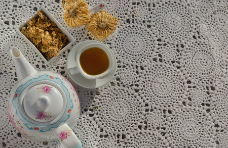 Chinese chrysanthemum flower tea and Dried chrysanthemum flower on crochet cotton Lace table placemat. Healthy beverage for drink. Herbs and medical concept. Space for text, Selective focus.の写真素材
