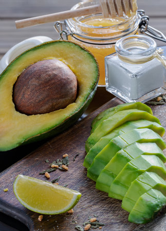Fresh organic sliced avocado and Sliced avocado halves with lime slice on a wooden cutting board...