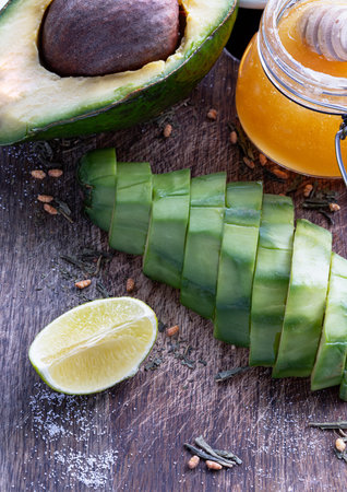 Fresh organic sliced avocado and Sliced avocado halves with lime slice on a wooden cutting board...