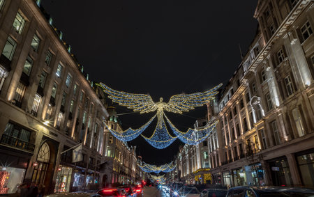 London, UK - Dec 25, 2023 - Flying angel Christmas decoration led lights display. Dramatic view of the traditional Christmas decoration lights hanging above Regent Street during dusk, The Spirit of Christmas, Light Festival in London, Space for text, Seleのeditorial素材