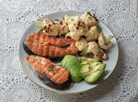 Breakfast is including Two Salmon steak with Cut an Avocado and Cauliflower on Ceramic plate. Organic and Healthy food. Oblique view from the top, Space for text, Selective focus.の写真素材