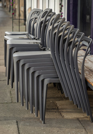 Pile of stacking silver gray plastic chairs are beside of The cafe terrace at sunny day. Detailed of pattern stack plastic chairs, Space for text, Selective focus.の写真素材
