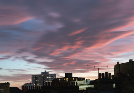 View of buildings and house during stunning beauty sunset and teal evening sky with dramatic clouds. Divine glow through the Clouds of the Evening warm Sun over Large Metropolitan city, Space for text, Selective focus.の写真素材