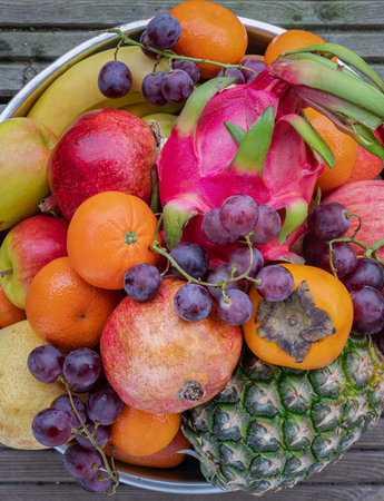 Variety of Fresh assorted fruits include Pineapple, Dragon fruit, Orange, Bananas, Black seedless grapes, Persimmon, pomegranate, apple and pear. Colorful healthy fruits background, Space for text, Selective focus.の写真素材